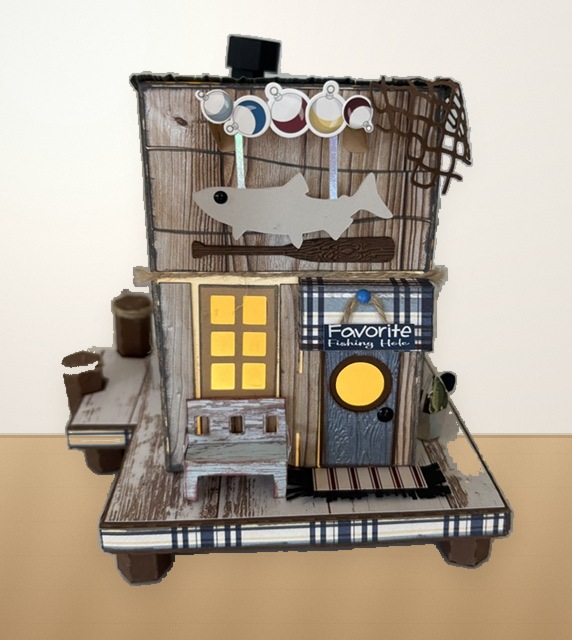 Front detail of the Bait House showing the fish sign, plaid awning, front door, porch bench, and layered paper textures